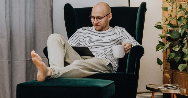 Mand sidder i stole med bare tæer, komfortabel varme i hjemmet